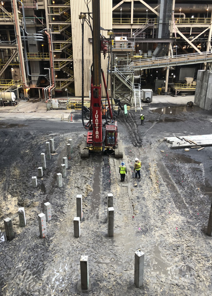 Workers and pile driver on construction site