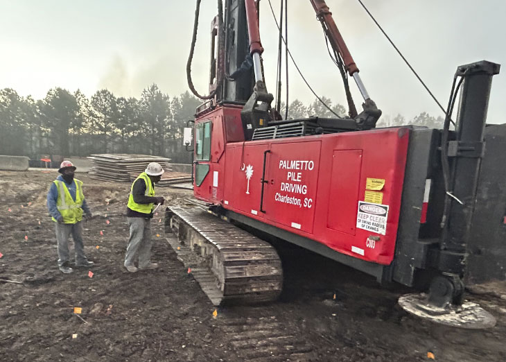 Workers and pile driver on construction site