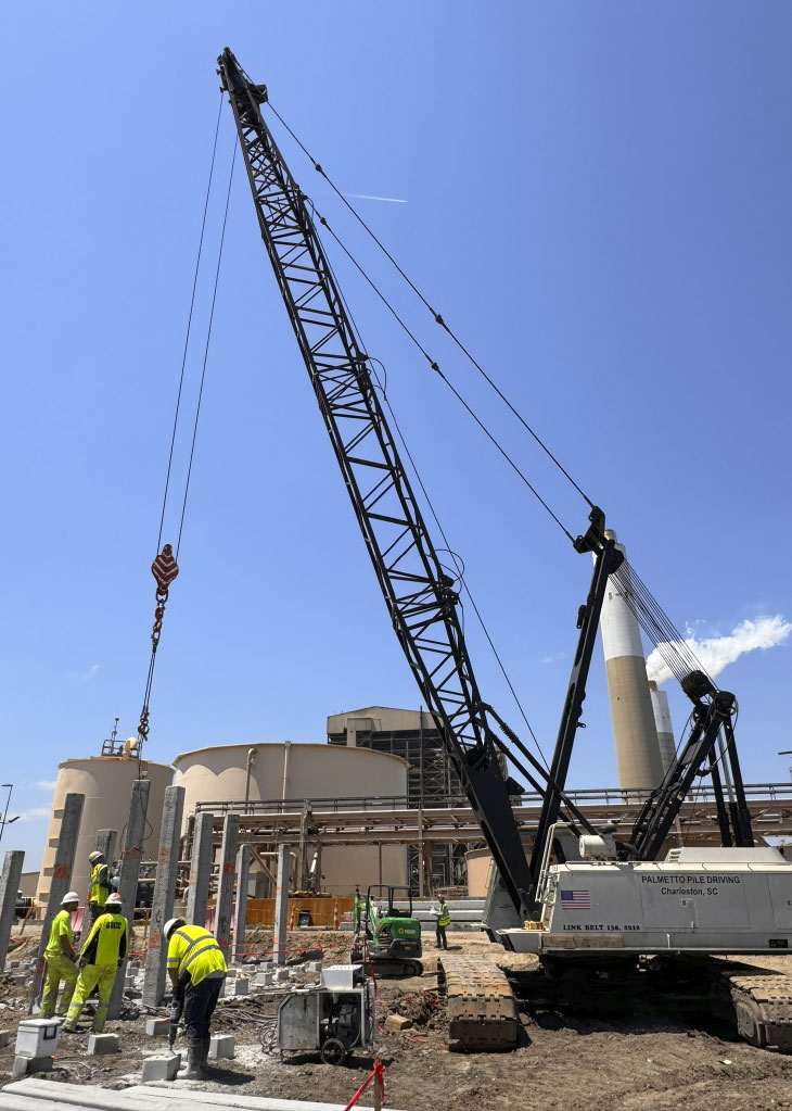 Workers and pile driving machine on construction site
